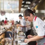 a group of people in a kitchen preparing food. smart security camera installation