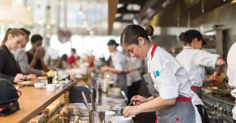 a group of people in a kitchen preparing food. smart security camera installation