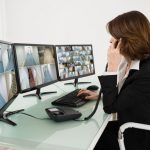 a woman sitting in front of a computer monitor talking on a phone.