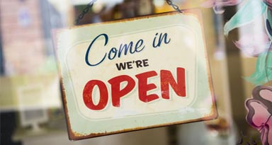 a sign hanging from a glass door that says, come in we're open.
