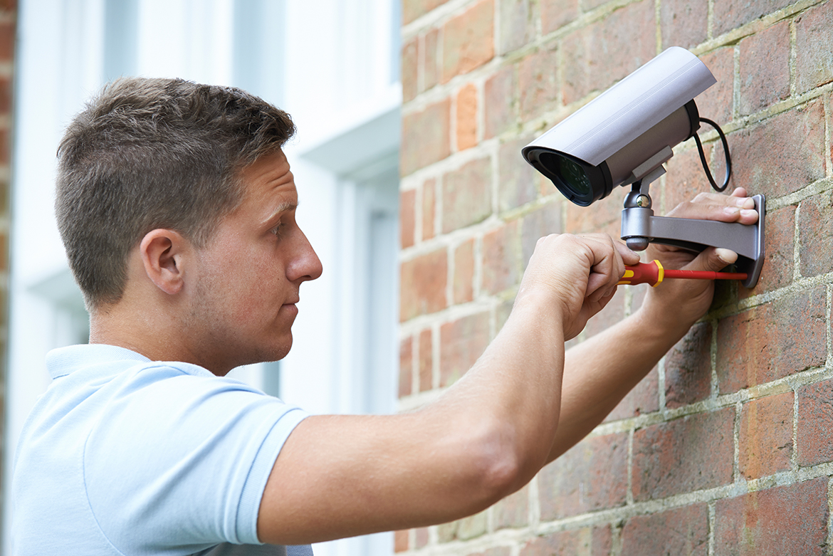 a man with a camera on a brick wall.